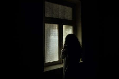 Horror silhouette inside abandoned creepy room with window at night. horror scene. Halloween...