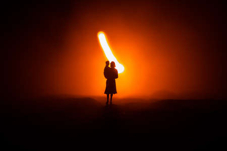 Silhouette of woman with child walking at cemetery at night. Horror Halloween concept. Artwork table...