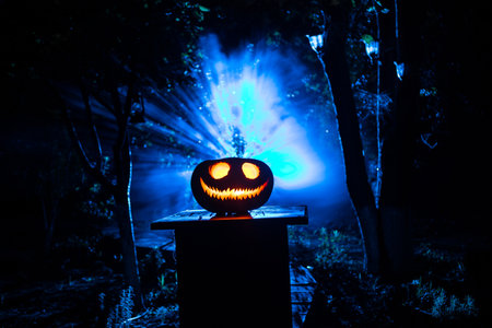 Pumpkin Burning In Forest at night. Scary Jack o Lantern smiling and glowing pumpkin with dark toned...