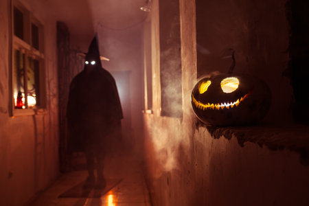 Halloween concept. Creepy silhouette in the dark corridor with pumpkin head. Toned light with fog on background. selective focus. long shutter shotの写真素材