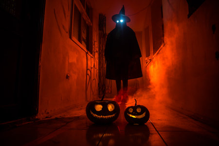 Halloween concept. Creepy silhouette in the dark corridor with pumpkin head. Toned light with fog on background. selective focus. long shutter shotの写真素材