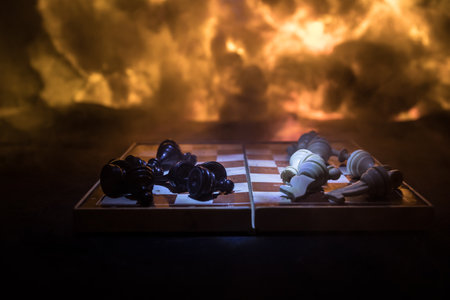 Chess board game concept of business ideas and competition or war theme. Chess figures on a dark background of explosion and fire clouds. selective focusの写真素材