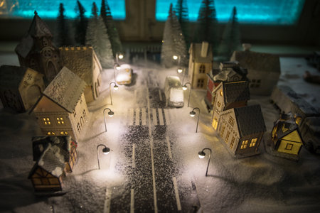 Little decorative cute small houses in snow at night in winter, Christmas and New Year miniature house in the snow at night with fir tree. Holiday concept. Selective focusの写真素材