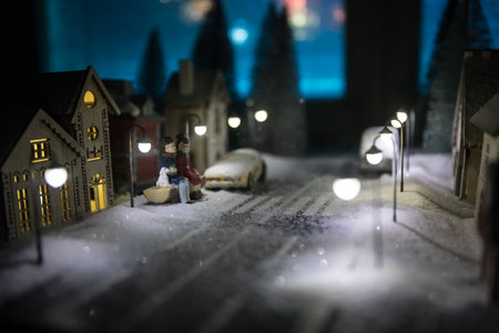 Little decorative cute small houses in snow at night in winter, Christmas and New Year miniature house in the snow at night with fir tree. Holiday concept. Selective focusの写真素材