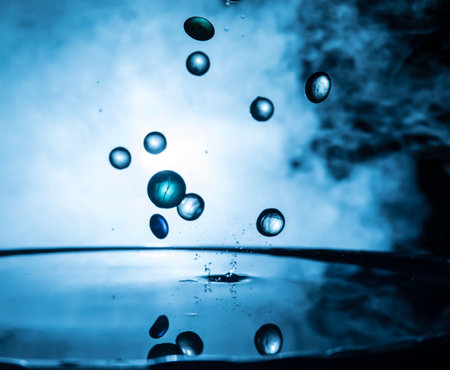 Colorful transparent stones dropping on water or water splash on dark foggy background. selective focus.の写真素材