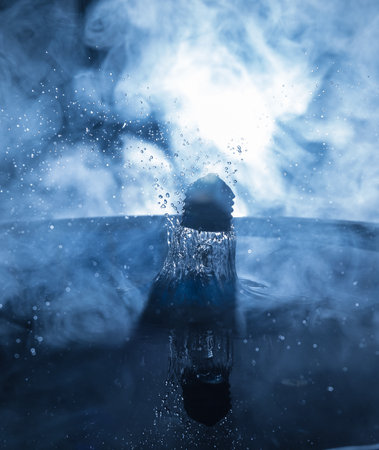 abstract concept. Light bulb dropping on water or water splash on dark foggy background. selective focus.の写真素材