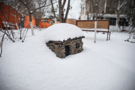 a little stone house covered with snow at the garden during wintertime. Decorative little house.の写真素材
