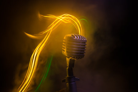Microphone for sound, music, karaoke in audio studio or stage. Mic technology. Speech broadcast equipment. Microphone in dark room on table with backlight. selective focusの写真素材