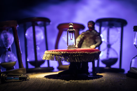 time concept. Man sitting on table with hourglass. Abstract hourglasses with smoke and lights on a dark background. Surreal decorated pictureの写真素材
