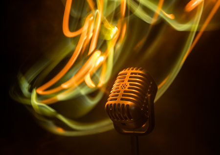 Microphone for sound, music, karaoke in audio studio or stage. Mic technology. Speech broadcast equipment. Microphone in dark room on table with backlight. selective focusの写真素材