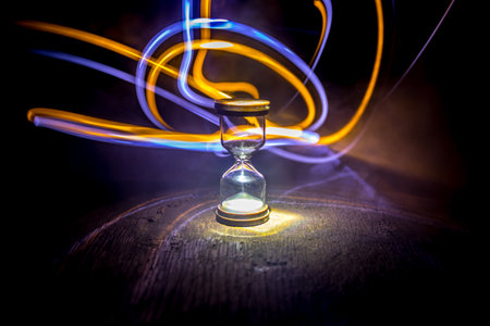 Hourglass as time passing concept for business deadline, urgency and running out of time. Sandglass, egg timer on dark background showing the last second or last minute or time out. With copy space.の写真素材