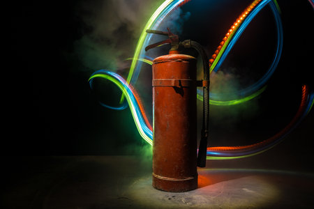 fire protection concept. Old fire extinguisher on dark foggy background with light. selective focusの写真素材
