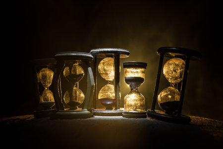 Hourglass as time passing concept for business deadline, urgency and running out of time. Sandglass, egg timer on dark background showing the last second or last minute or time out. With copy space.の写真素材