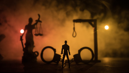 Legal law or crime and execution concept. Death penalty miniatures on table. Man alone looking to execute at night. Artwork decoration with handcuffs, Statue of Justice and mallet of justiceの写真素材