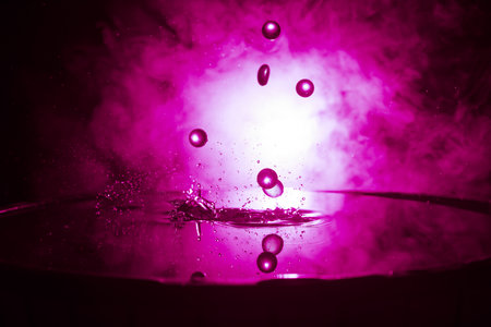 Colorful transparent stones dropping on water or water splash on dark foggy background. selective...