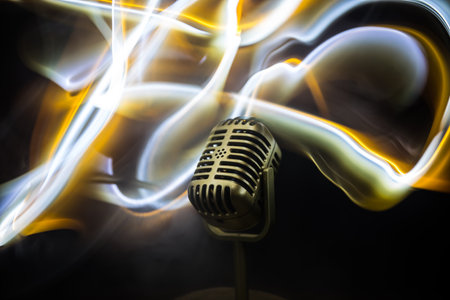 Microphone for sound, music, karaoke in audio studio or stage. Mic technology. Speech broadcast equipment. Microphone in dark room on table with backlight. selective focusの写真素材