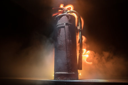 fire protection concept. Old fire extinguisher on dark foggy background with light. selective focusの写真素材