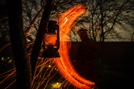 Beautiful colorful illuminated lamp in the garden in misty night. Retro style lantern at night...