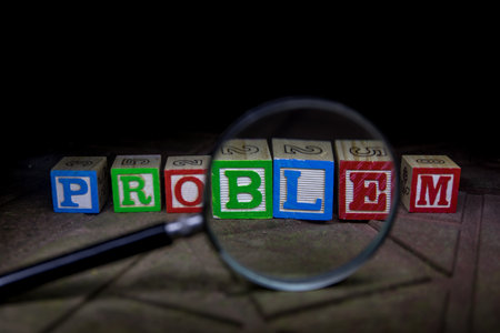 Loupe analyzing the word problem on wooden cubes in dark backgroung. selective focus