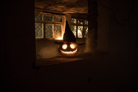 Scary Halloween pumpkin in the mystical house window at night or halloween pumpkin in night on...