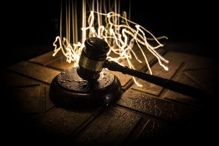 Law theme, mallet of the judge on wooden desk. Law gavel on dark foggy background with light. selective focusの写真素材