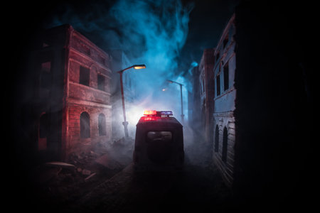 Police raid at night and you are under arrest concept. Silhouette of a police car on the backside. Image with the flashing red and blue police lights at foggy background.の写真素材