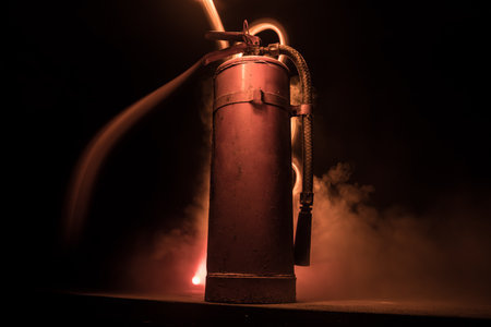 fire protection concept. Old fire extinguisher on dark foggy background with light. selective focusの写真素材