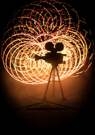 movie concept. Miniature movie set on dark toned background with fog and empty space. Silhouette of vintage camera on tripod. selective focusの写真素材