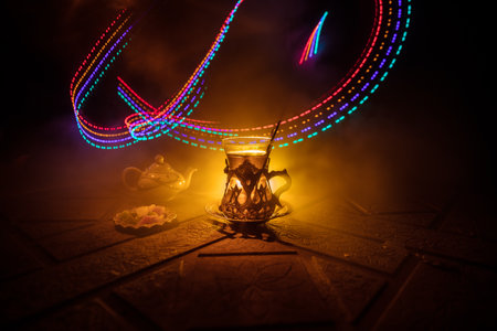 Arabian tea in glass with eastern snacks on a stone surface on dark background with lights and smoke. Eastern tea concept. selective focus.の写真素材