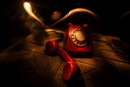 old red telephone on grunge stone surface with art dark background with fog and toned light. empty space. selective focusの写真素材