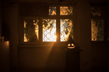 Scary Halloween pumpkin in the mystical house window at night or halloween pumpkin in night on abandoned room with window. selective focusの写真素材