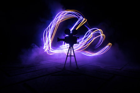 movie concept. Miniature movie set on dark toned background with fog and empty space. Silhouette of vintage camera on tripod. selective focusの写真素材