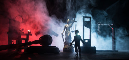 Legal law or crime and execution concept. Death penalty miniatures on table. Man alone looking to execute at night. Artwork decoration with handcuffs, Statue of Justice and mallet of justiceの写真素材