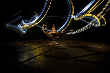 Antique Aladdin arabian nights genie style oil lamp with soft light white smoke, Dark background. Lamp of wishes conceptの写真素材