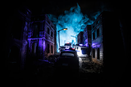 Police raid at night and you are under arrest concept. Silhouette of a police car on the backside. Image with the flashing red and blue police lights at foggy background.の写真素材