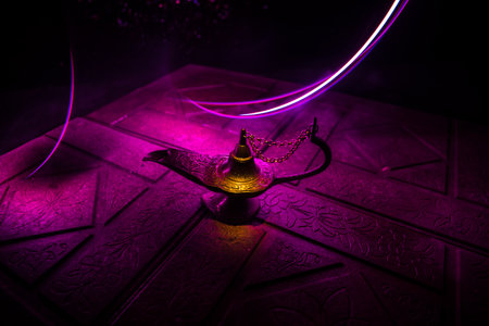 Antique Aladdin arabian nights genie style oil lamp with soft light white smoke, Dark background. Lamp of wishes conceptの写真素材
