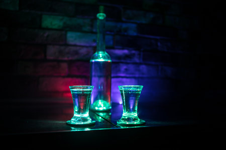 Cold vodka glass on a dark background in the neon light or glasses of russian vodka on bar background. selective focusの写真素材