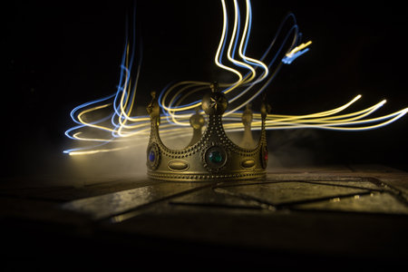 low key image of beautiful kings crown over wooden table. vintage filtered. fantasy medieval period. selective focus. colorful backlightの写真素材