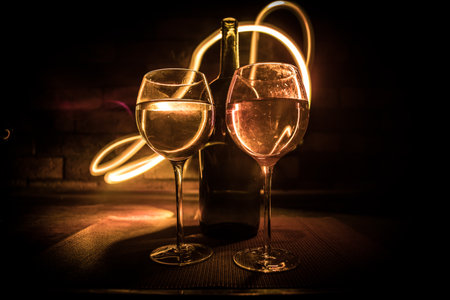 Wine glass on dark bar background low light. Colorful wine glasses with light on backside in selective focusの写真素材