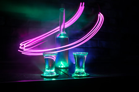 Cold vodka glass on a dark background in the neon light or glasses of russian vodka on bar...