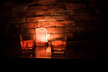 Whiskey drink concept. Glass of whiskey and ice with color light and fog on dark bar background. selective focusの写真素材