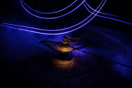 Antique Aladdin arabian nights genie style oil lamp with soft light white smoke, Dark background. Lamp of wishes conceptの写真素材