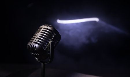 Microphone for sound, music, karaoke in audio studio or stage. Mic technology. Speech broadcast equipment. Microphone in dark room on table with backlight. selective focusの写真素材