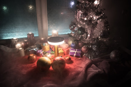 Christmas and New year concept.Fir tree standing on red carpet with traditional holiday attributes. Cozy window with colorful lights on background. selective focusの写真素材