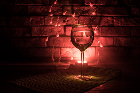 Wine glass on dark bar background low light. Colorful wine glasses with light on backside in selective focusの写真素材