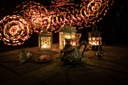 Arabian tea in glass with eastern snacks on a stone surface on dark background with lights and smoke. Eastern tea concept. selective focus.の写真素材