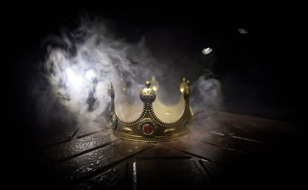low key image of beautiful kings crown over wooden table. vintage filtered. fantasy medieval period. selective focus. colorful backlightの写真素材