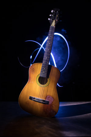 music concept. Acoustic guitar isolated on a dark background under beam of light with smoke with copy space. Guitar Strings, close up. selective focus.の写真素材