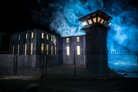 criminal justice concept. Old prison watchtower protected by wire of prison fence at night. creative art decoration. selective focusの写真素材