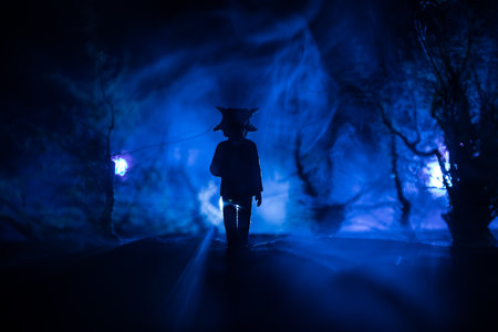 Silhouette of a person standing in the dark forest. Horror halloween concept. strange silhouette in a dark spooky forest at nightの写真素材